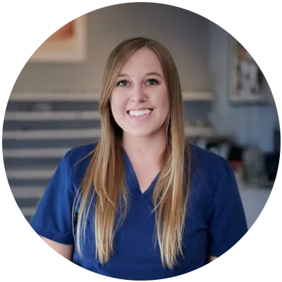 Smiling woman with long blonde hair wearing blue scrubs.