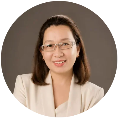 Smiling woman wearing glasses and a light-colored blazer.